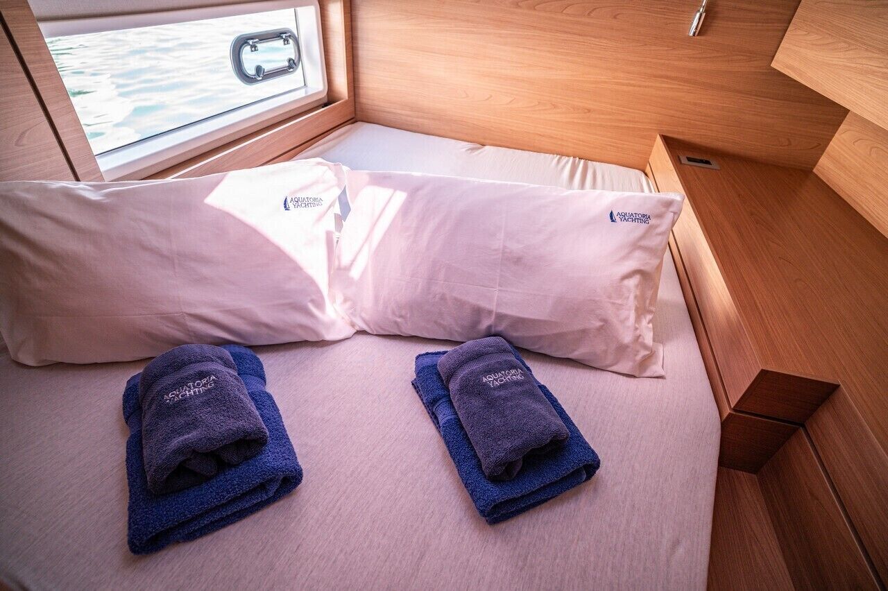 A compact room with a bed, pillows, and towels.