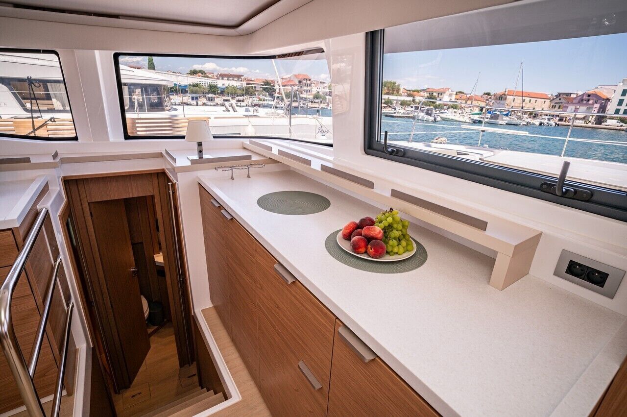 A modern kitchen with a view of a marina, wooden cabinets, and a fruit plate on the counter.