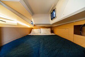 Ein kleines, gut beleachtetes Kabinenzimmer mit einem Einzelbett, einem kleinen Fenster und eingebauten Ablagefächern.