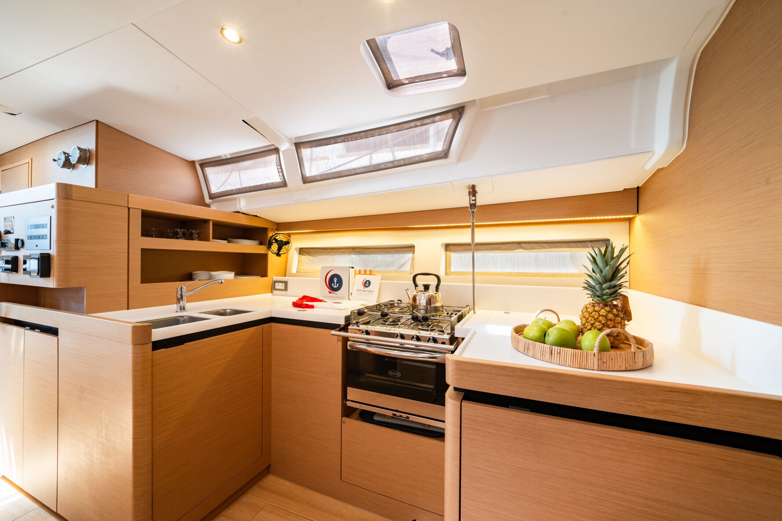 Una cocina compacta con estufa, horno y pileta integrados, muebles de madera y tragaluces.