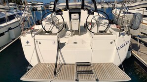 Un barco llamado 'MARLEY' amarrado en un puerto deportivo con varios otros barcos, un timón y un panel de control.