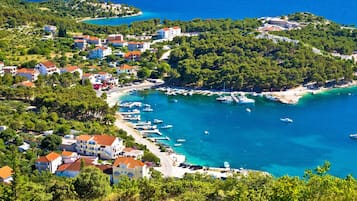 Un village côtier avec des maisons, un port de plaisance et des eaux d’un bleu limpide.