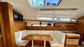 Una cocina compacta con una mesa de madera, asientos blancos acolchados, un microondas y un lavabo.