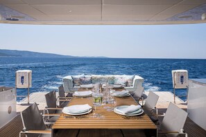 A dining table set on a boat deck with a view of the sea. - Sun-Kissed Sailing Adventure in Split, Croatia (Kaštel Gomilica)