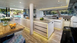 Una cocina moderna con una isla central, un comedor con mesa de madera y vistas al exterior.