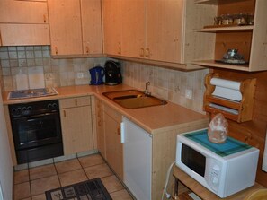 A compact kitchen with a stove, sink, and microwave.