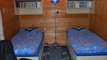 Ein kleines Zimmer mit zwei Einzelbetten, einem Schreibtisch und zwei Bücherregalen.