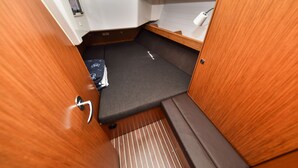 Un espacio para dormir compacto con un colchón, un estante pequeño y una puerta de madera.