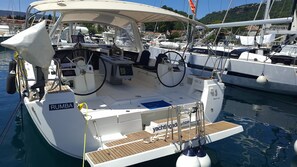 A yacht with a covered deck, a steering wheel, and a name 'RUMBA' on the side.