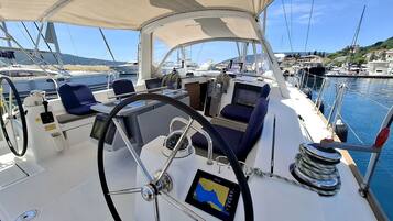 Le pont d’un bateau, avec un volant, un panneau de commande et un espace pour s’asseoir.