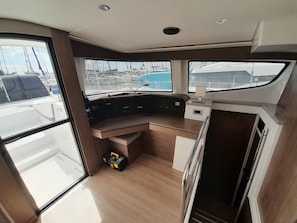 A boat's interior with a control station, windows, and a small storage box. - Sun-Kissed Sailing Adventure in Islas Sarónicas (Alimos)