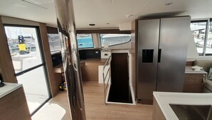 A modern kitchen with stainless steel appliances, a wooden countertop, and a view of the sea through the windows. - Sun-Kissed Sailing Adventure in Islas Sarónicas (Alimos)