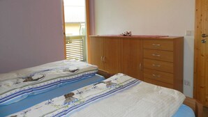Un dormitorio con dos camas, un armario de madera y una ventana con persianas.