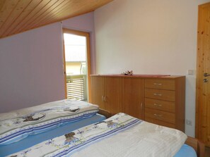 A bedroom with two beds, a wooden wardrobe, and a window with blinds. - Panorama, Chalet Appartement/Fewo, Dusche oder Bad, WC 7-Bettwohnung by Interhome (Zweisimmen)