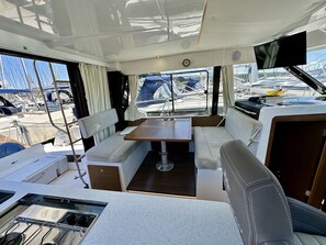 A boat's interior with a dining area, a small kitchen, and a TV. - Sun-Kissed Sailing Adventure in Zadar, Croatia (Drage)