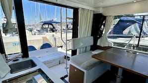Bootinterieur met een keukenhoek, zitplaatsen en uitzicht op de jachthaven.