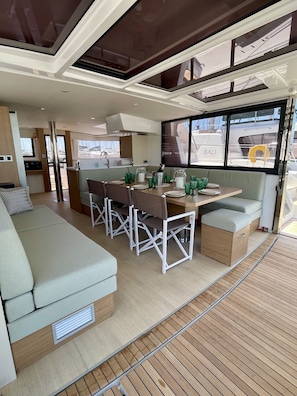 A modern kitchen with a dining area, a sofa, and a view of the marina. - Sun-Kissed Sailing Adventure in Islas Sarónicas (Alimos)