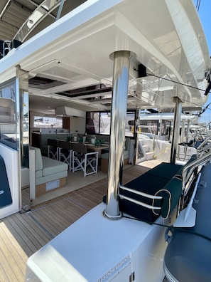 A yacht's deck with a covered seating area, a bar, and a view of other yachts. - Sun-Kissed Sailing Adventure in Islas Sarónicas (Alimos)