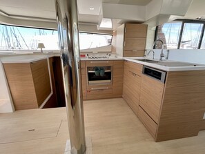 A compact kitchen with wooden cabinets, a built-in oven, and a dishwasher. - Sun-Kissed Sailing Adventure in Islas Sarónicas (Alimos)