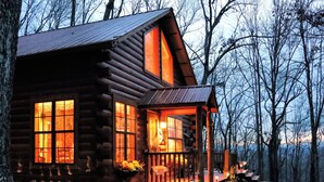 Una baita di legno con ampie finestre, un portico e un braciere.
