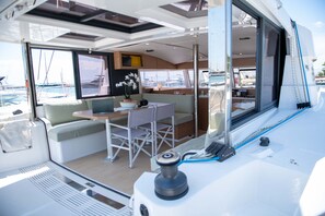 A yacht interior with a dining area, seating, and a view of the marina. - Sun-Kissed Sailing Adventure in the Ionian Islands, Lefkada (Lefkada)