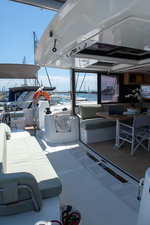 A yacht interior with a dining area, seating, and a view of the marina. - Sun-Kissed Sailing Adventure in the Ionian Islands, Lefkada (Lefkada)
