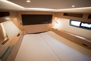 Ein modernes, helles Zimmer mit einem großen Bett, integriertem Fernseher und Holzvertäfelung.