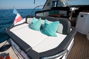 Ein Bootsdeck mit Sitzgelegenheiten, einer Flagge und einem kleinen Tisch.