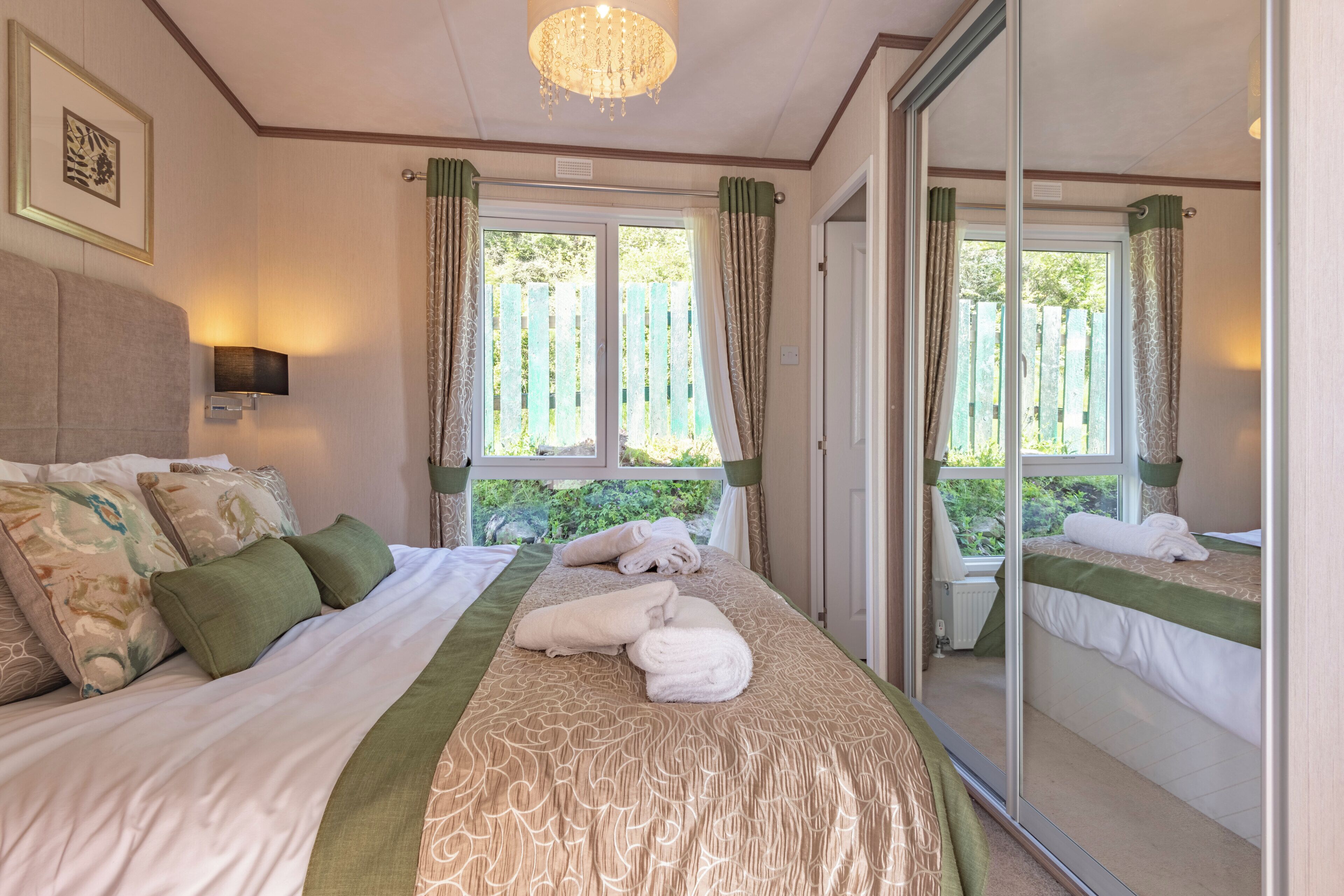 Un dormitorio con una cama grande, un espejo y vistas a zonas verdes.