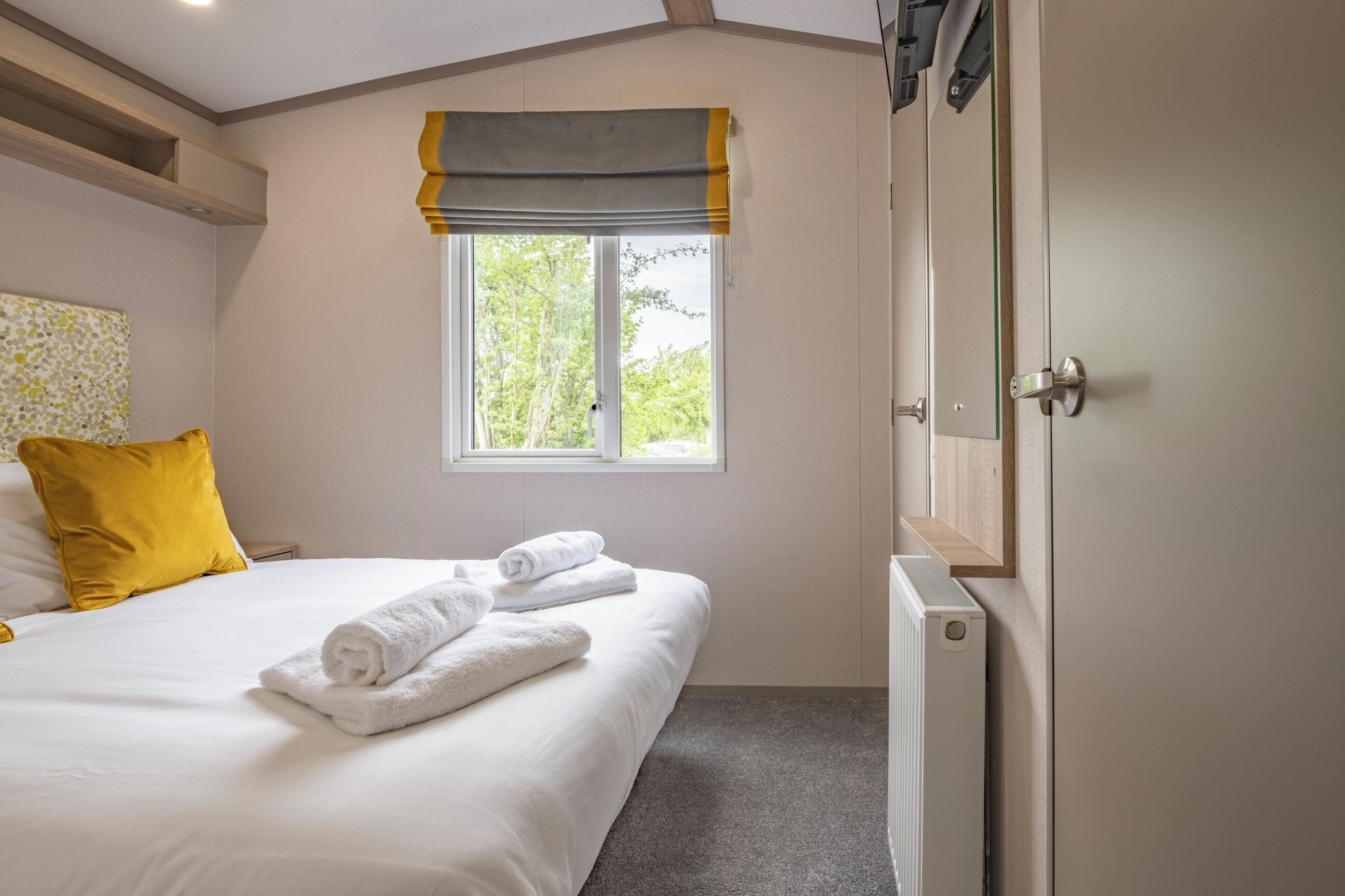 Una camera da letto con un letto, una finestra con tende, un termosifone e una porta.