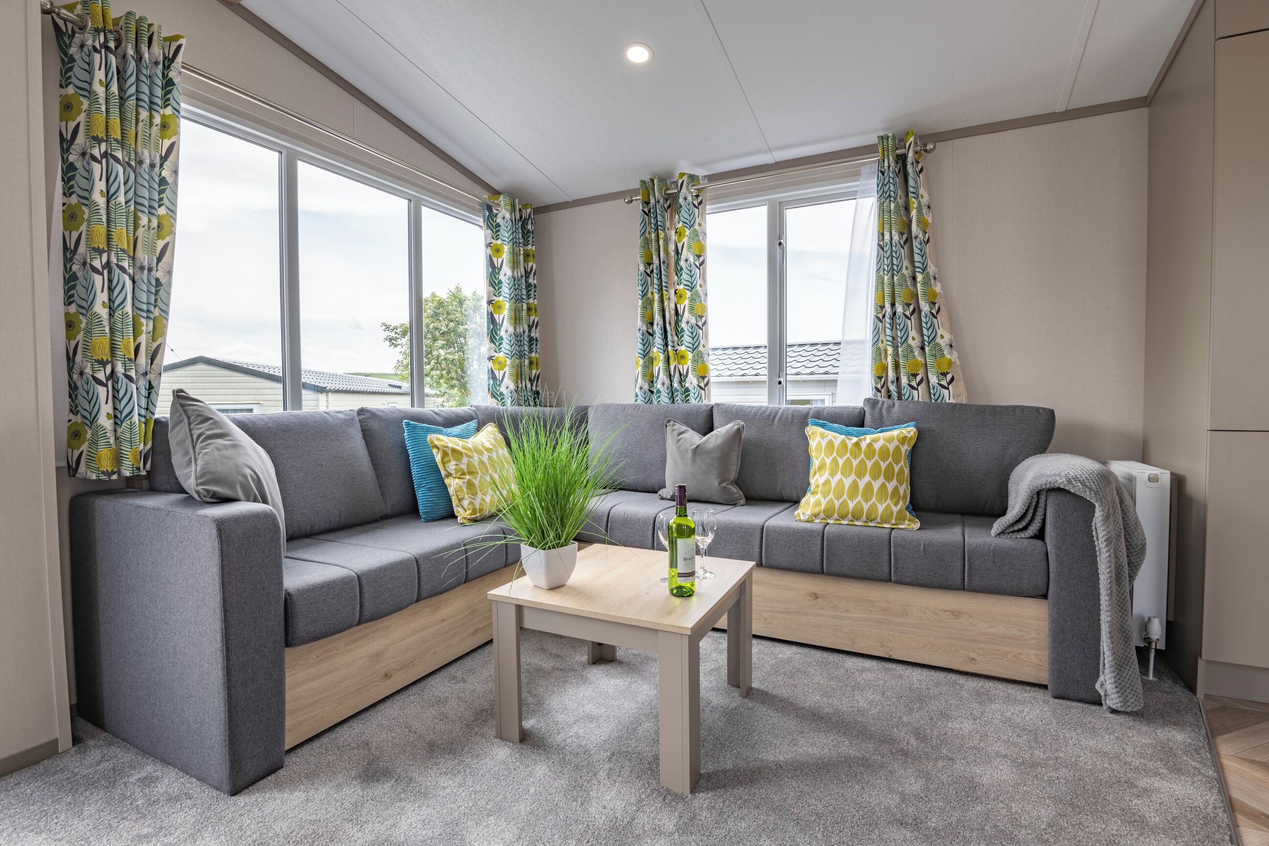 A modern living room with a grey sofa, a wooden coffee table, and a potted plant.