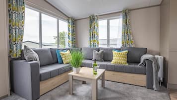 Un salón moderno con un sofá gris, una mesa de centro de madera y una planta en maceta.