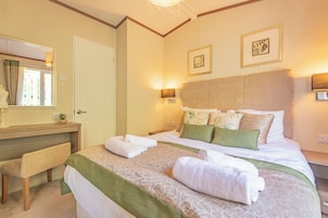 Una habitación de hotel con una cama, un banco, un espejo y dos lámparas de pared.