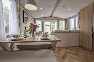 Una cocina moderna con una mesa de comedor para dos, un florero con flores y vistas al exterior.