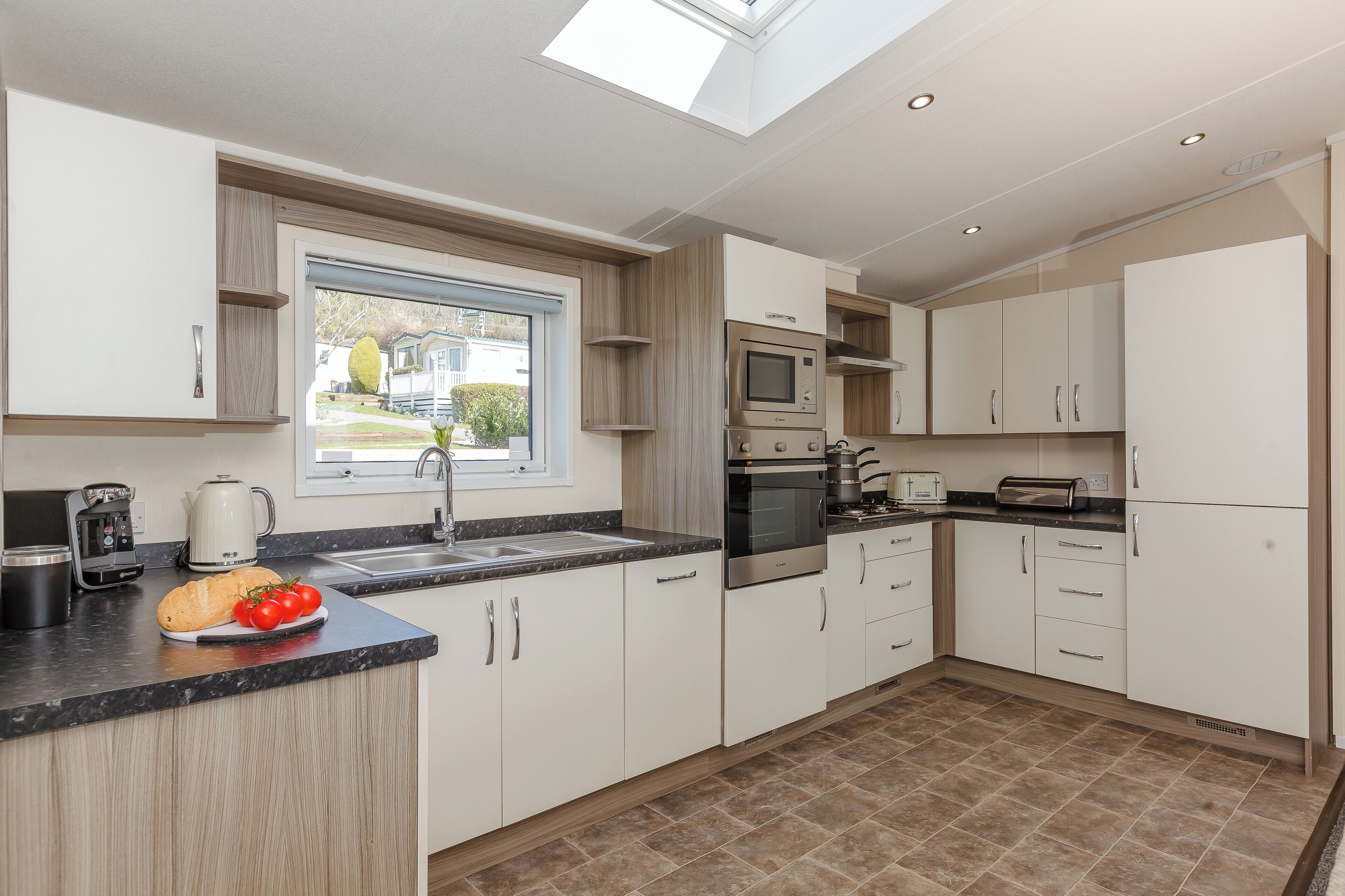 A modern kitchen with a skylight, built-in appliances, and a view of the outside.