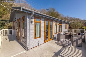 A single-story building with a covered deck, large windows, and a small outdoor seating area. - Tan Rallt Holiday Park & Spa (Abergele)