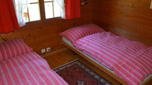 A room with two single beds, a window with curtains, and a patterned rug. - Arduus Appartement/Fewo, Dusche oder Bad, WC 4-Bettwohnung by Interhome (Gstaad)
