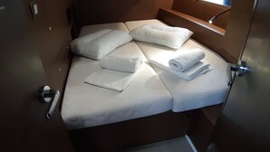 A bed with pillows and a rolled towel, a bedside table, and a window with a view. - Sun-Kissed Sailing Adventure in the Ionian Islands, Lefkada (Lefkada)