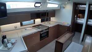 A compact kitchen with a stove, oven, and a small dining area with a tray of cups and a kettle. - Sun-Kissed Sailing Adventure in the Ionian Islands, Lefkada (Lefkada)