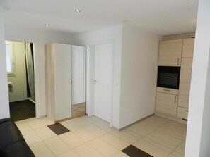 A room with a wardrobe, a door, and a kitchen area with cabinets. - Schön-Egg Appartement/Fewo, Dusche, WC 2-Bettwohnung by Interhome (Zweisimmen)