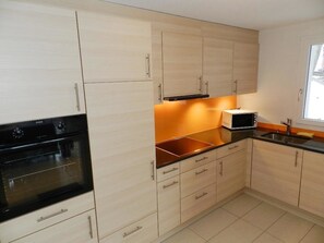 A kitchen with light wood cabinets, a black oven, a microwave, and a sink. - Schön-Egg Appartement/Fewo, Dusche, WC 2-Bettwohnung by Interhome (Zweisimmen)