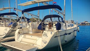 A sailboat docked at a marina with multiple masts and flags, a cabin with windows, and a deck area. - Sun-Kissed Sailing Adventure in Zadar, Croatia (Drage)