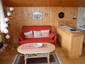 A cozy living room with a red sofa, a wooden cabinet, and a small table with a bowl. - Résidence Sonnegg (Herrli) Appartement/Fewo, Dusche oder Bad, WC 4-Bettwohnung by Interhome (Zweisimmen)