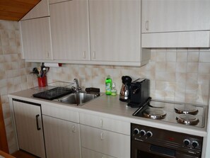 A kitchen with a sink, stove, and cabinets. - Résidence Sonnegg (Herrli) Appartement/Fewo, Dusche oder Bad, WC 4-Bettwohnung by Interhome (Zweisimmen)