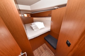 A compact, well-lit cabin with a single bed, a small seating area, and a built-in bench. - Sun-Kissed Sailing Adventure in Zadar, Croatia (Bibinje)