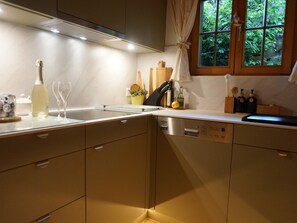 Eine moderne Küche mit eingebautem Geschirrspüler, einer Weinflasche und Weingläsern auf der Arbeitsfläche.