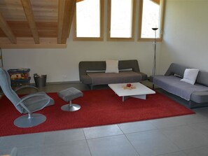 A living room with a grey sofa, a red rug, a white coffee table, and a grey armchair.