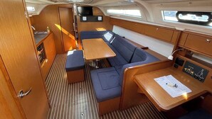 Interior de barco com área de refeições, assentos, painel de controle e televisão.