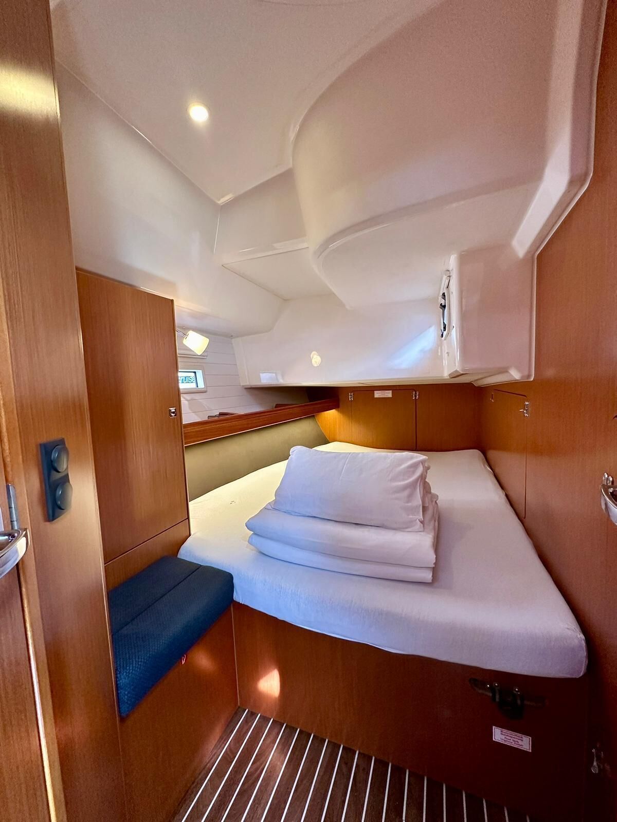 A compact cabin with a bed, a small seating area, and a storage cabinet.