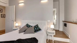 Ein Hotelzimmer mit einem Bett, Nachttischen, einem Spiegel und einem Holzboden.